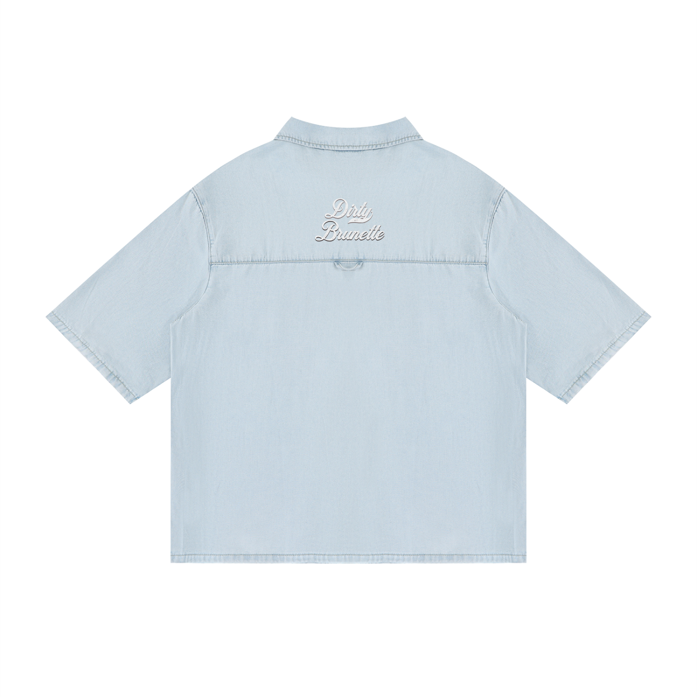 back view of a light blue, short-sleeve button-up shirt with a subtle faded finish and a small raised “Dirty Brunette” Milkstore script logo centered across the upper back.