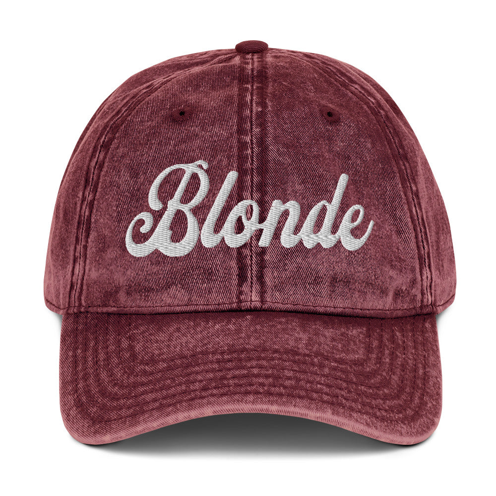 flatlay of maroon denim vintage wash effect baseball cap with the word 'Blonde' embroidered on the front in white adventure font 