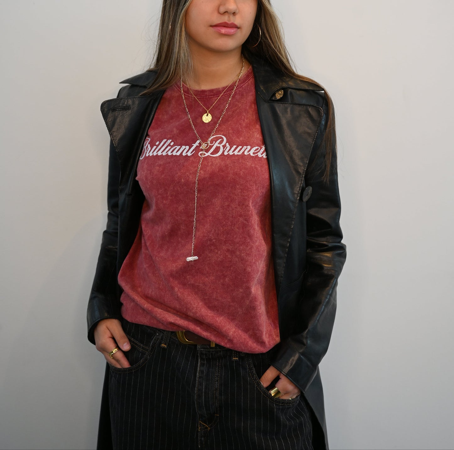 brunette wears a garnet red unisex loose-fit denim wash t-shirt with vintage Coca-Cola-inspired milkstore script in white reading ‘Dirty Brunette’ on the front. Branded RedBlonde on the inside neck and right shoulder in red