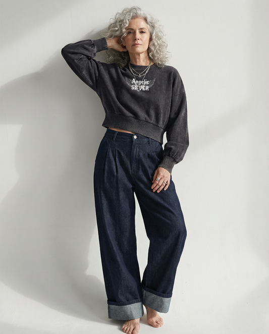 model wears a black mineral-wash cropped sweater with balloon sleeves, ribbed collar/cuffs/waistband, and a white “Angelic silver” wing graphic on the chest