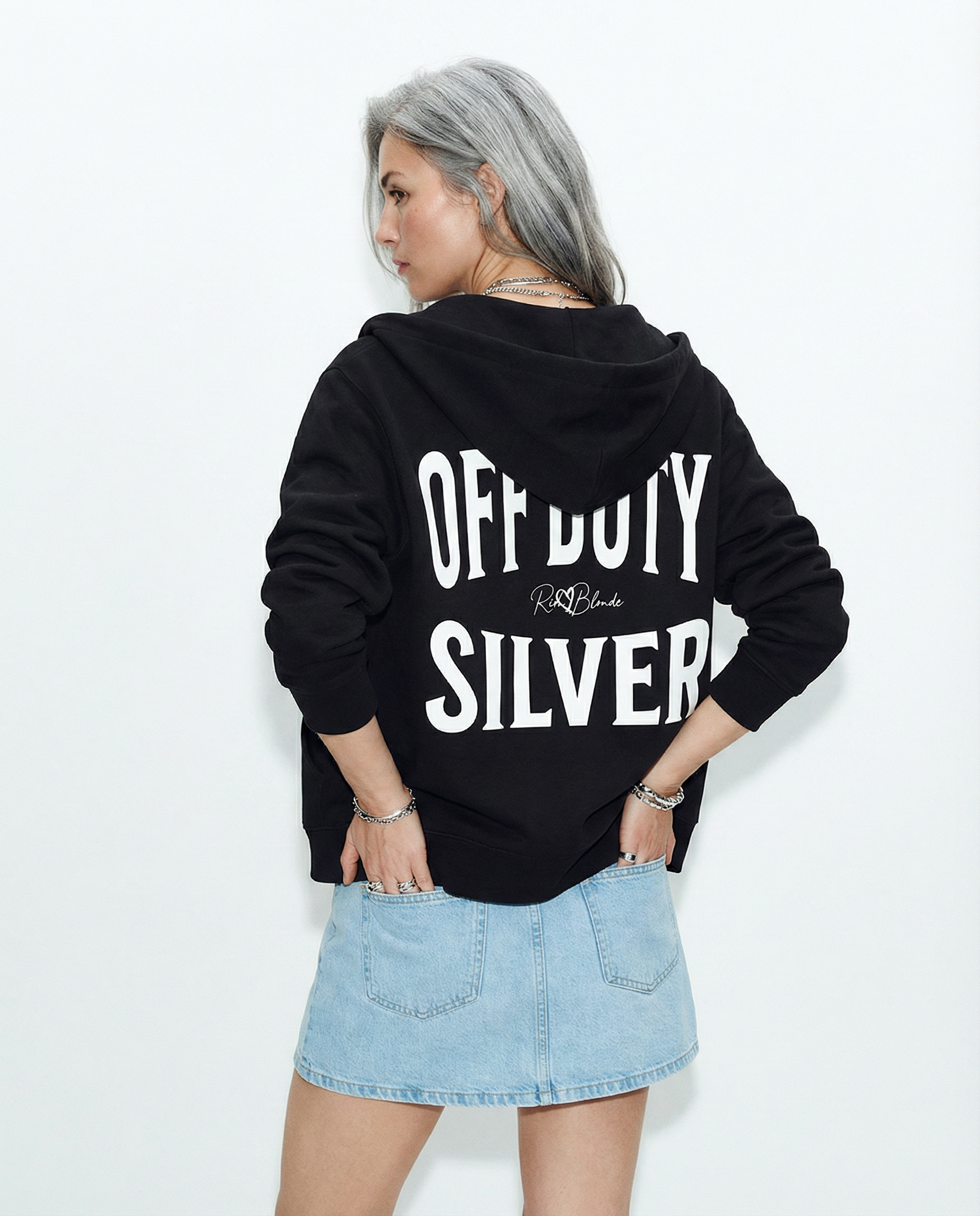 model wears a black oversized hoodie shown from the back on a white background, featuring large white “OFF DUTY SILVER” Brookfield text with a small RedBlonde script logo between the words.