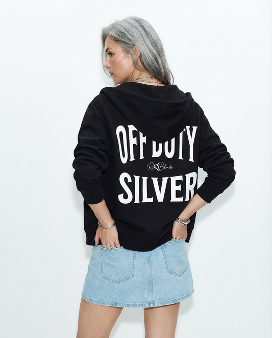 model wears a black oversized hoodie shown from the back on a white background, featuring large white “OFF DUTY SILVER” Brookfield text with a small RedBlonde script logo between the words.