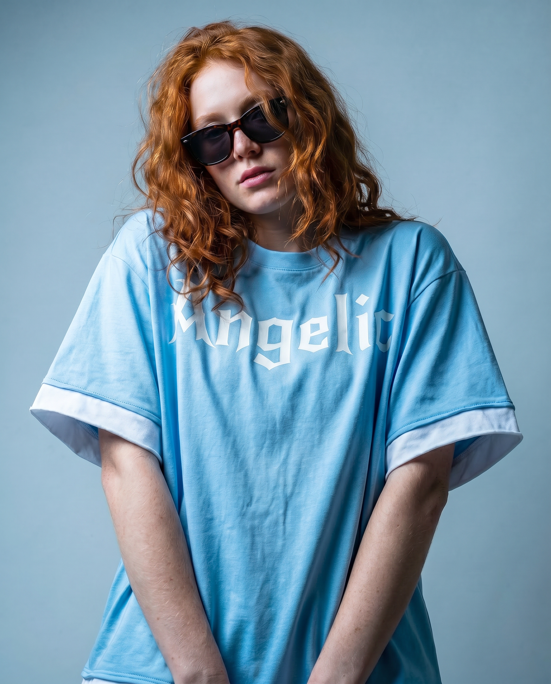 model wears a Light blue boxy short sleeve t-shirt with white layered trim and Angelic graphic in New Rocker graphic across the chest.