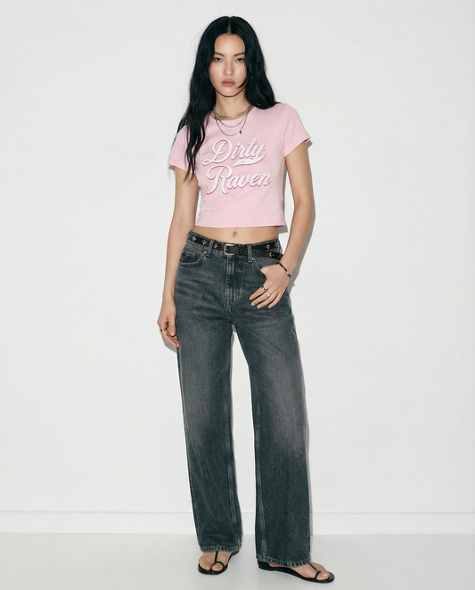 Model wears a Light pink short-sleeve crop T-shirt with large cursive “Dirty Raven” Milkstore text in white and pink on the front, 