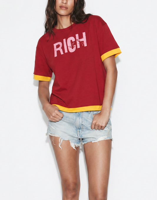 model wears a Red boxy short sleeve t-shirt with yellow layered trim and pink RICH graphic IN ED GEIN FONT on the chest.