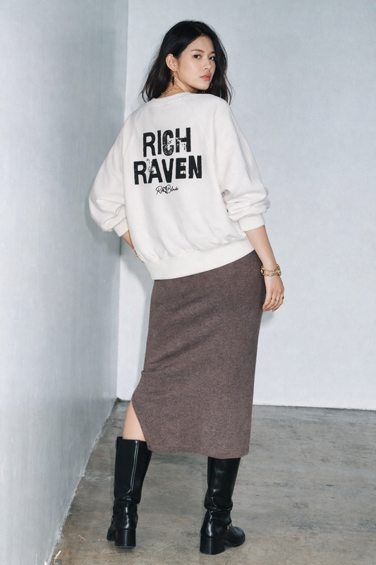 white oversized dolman-sleeve sweatshirt shown from the back. It has a boxy, relaxed fit with dropped shoulders, ribbed crew neckline, ribbed cuffs, and a ribbed hem band. Centered on the back is a distressed black “RICH RAVEN” Ed Gein graphic with a small “RedBlonde” script logo beneath.