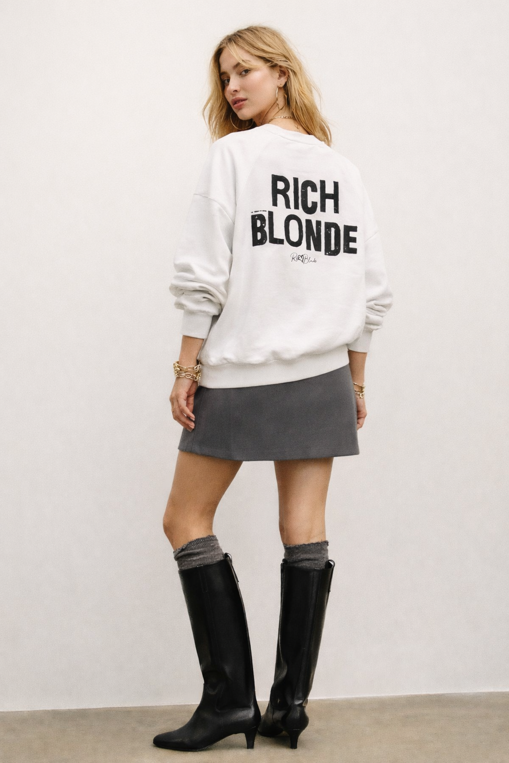 model wears a White oversized dolman-sleeve sweatshirt shown from the back on a plain white background. It has a boxy, relaxed fit with dropped shoulders, ribbed crew neckline, ribbed cuffs, and a ribbed hem band. Centered on the back is a distressed black “RICH BLONDE” Ed Gein graphic with a small “RedBlonde” script logo beneath.
