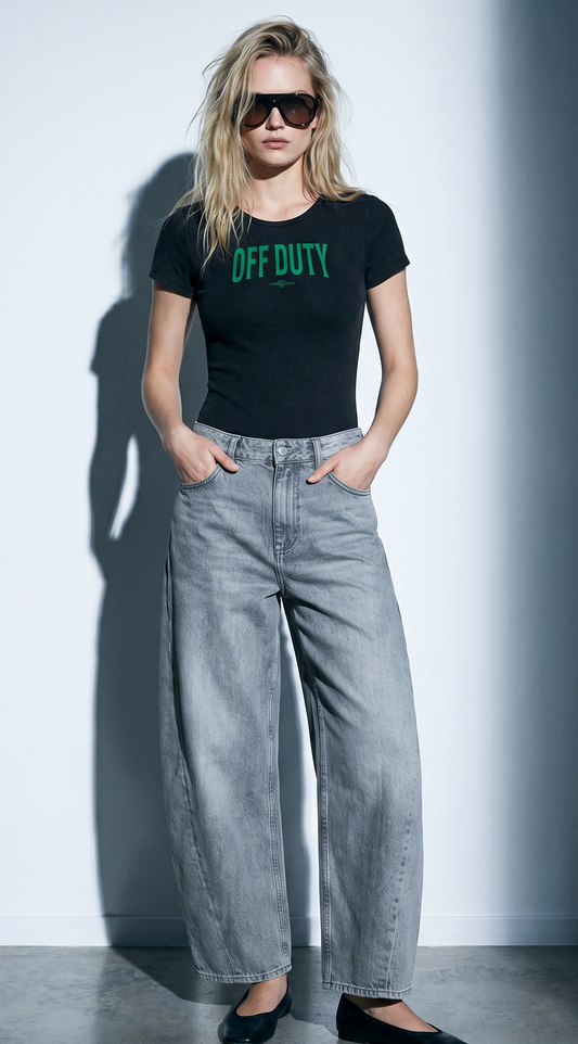 Model wears a Washed charcoal ribbed short sleeve bodysuit with a crew neckline and green collegiate 'Off Duty'   graphic at the chest.