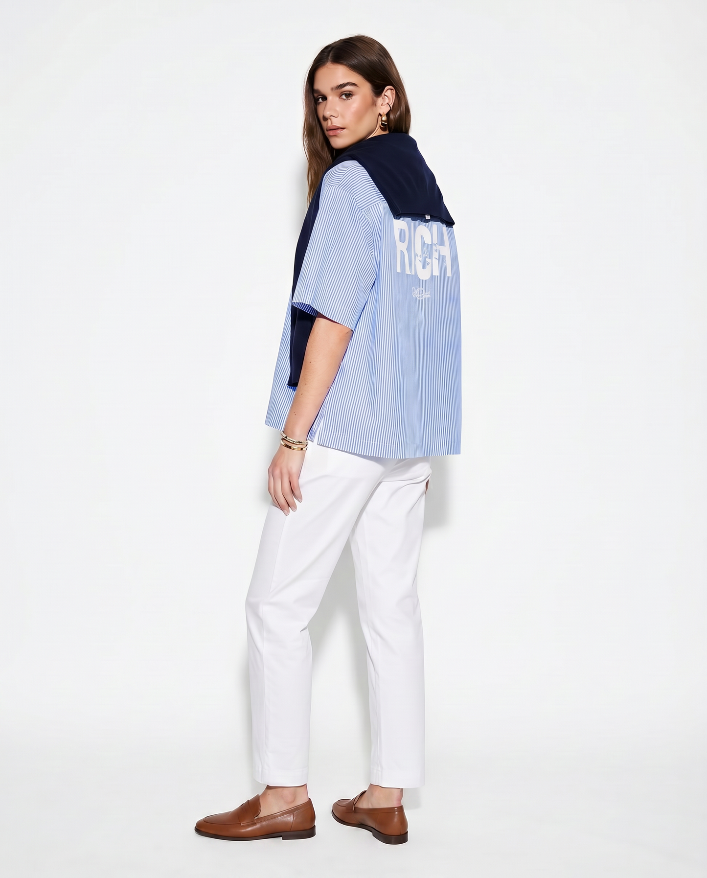 Model wears a light blue and white pinstriped short-sleeve button-up shirt with a large distressed white “RICH” Ed Gein font print across the upper back and a small RedBlonde script logo underneath.
