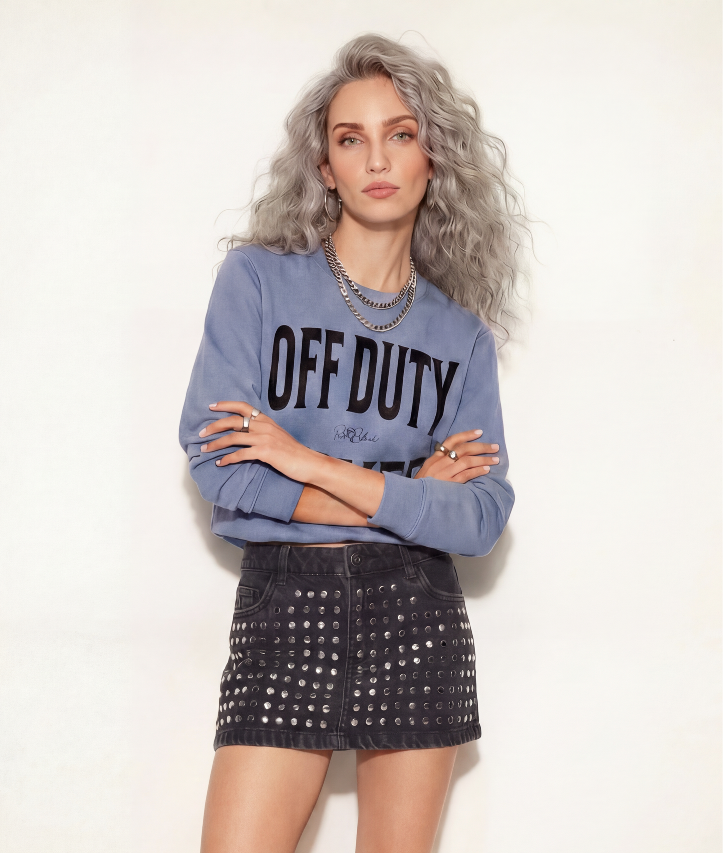 model wears a blue crewneck sweatshirt with a large black “OFF DUTY SILVER” graphic across the chest and a small RedBlonde script logo centered between the words.