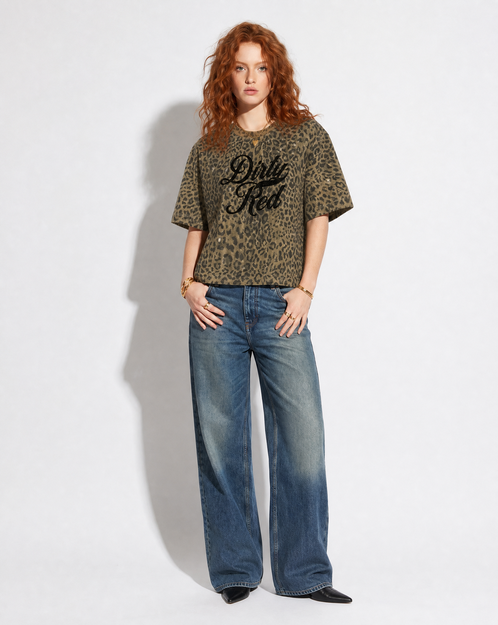 model wears brown/green oversized T-shirt with an all-over animal print, ribbed crew neckline, and faded black Dirty Red Milkstore script graphic across the front.