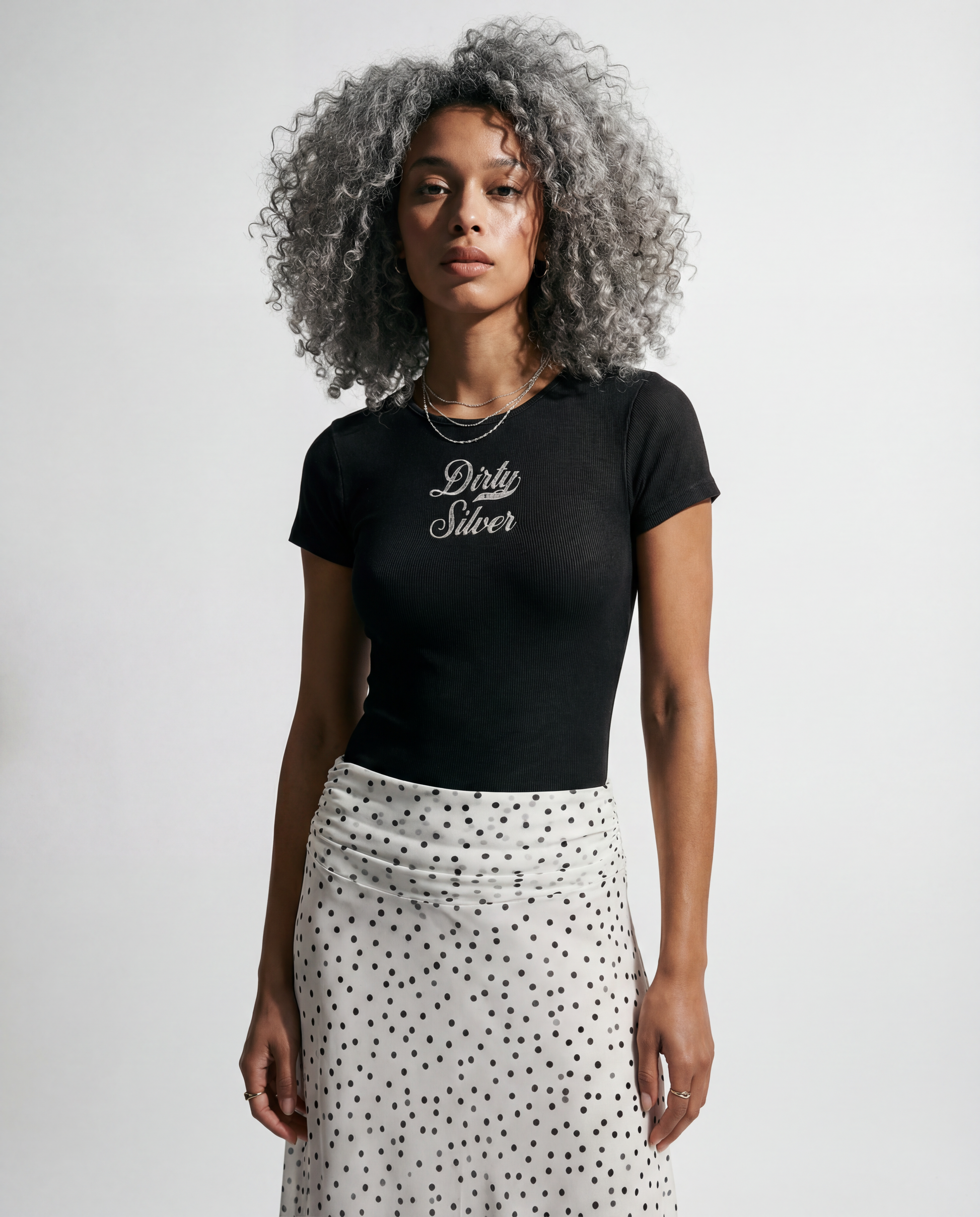 model wears Washed charcoal ribbed short sleeve bodysuit with a crew neckline and white Dirty Silver Milkstore font graphic at the chest.