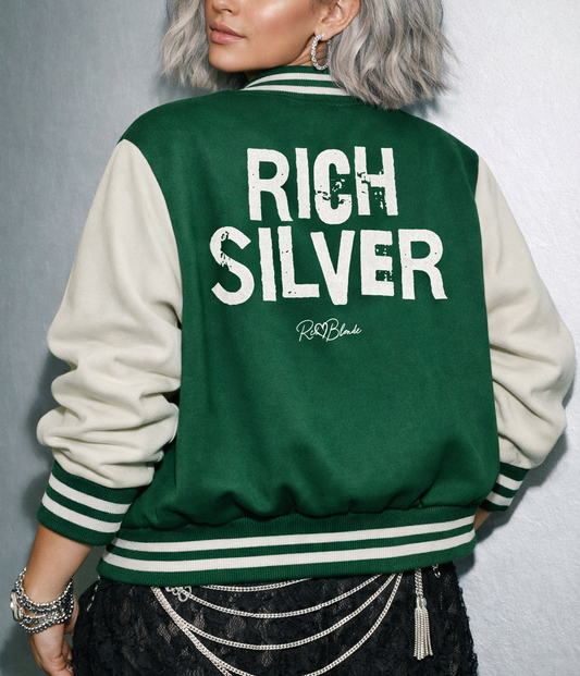 model wears green & white varsity-style jacket with cream sleeves and striped ribbed trims. The back features large white text reading “RICH SILVER” in Ed Gein font with a small RedBlonde signature logo in the centre between the words