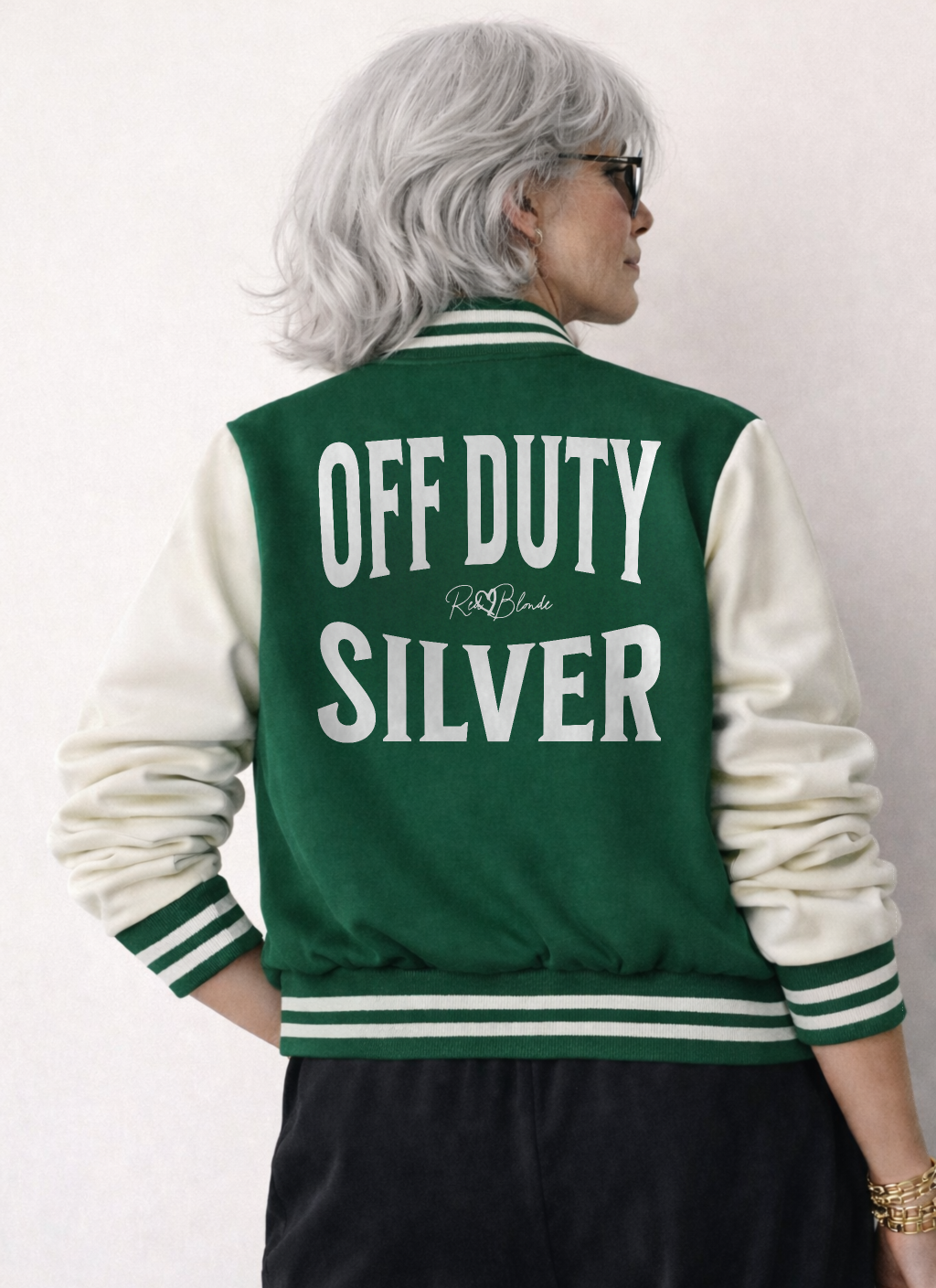 Model wears a green & white varsity-style jacket with cream sleeves and striped ribbed trims. The back features large white text reading “OFF DUTY SILVER” in Ed Gein font with a small RedBlonde signature logo in the centre between the words