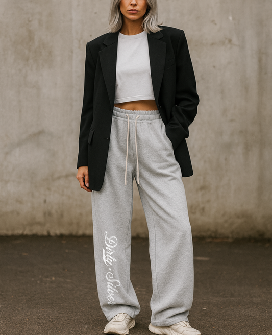 model with silver gray hair wears Grey relaxed-fit straight joggers with white drawstrings and vintage-style “Dirty Silver” milkstore script printed vertically down the leg — bold, effortless and unmistakably RedBlonde.