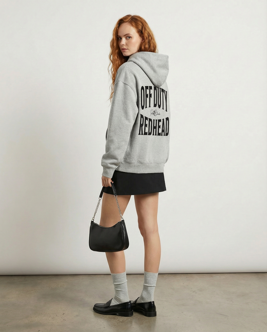model wears a grey oversized hoodie shown from the back on a white background, featuring large black “OFF DUTY REDHEAD” Brookfield text with a small RedBlonde script logo between the words.