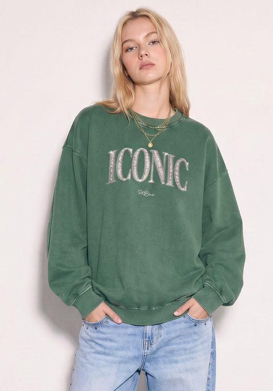 model wears a RedBlonde oversized acid-wash sweatshirt in sage green with diamanté-effect "ICONIC" graphic print on the chest and RedBlonde script logo beneath, crew neck, ribbed cuffs and hem