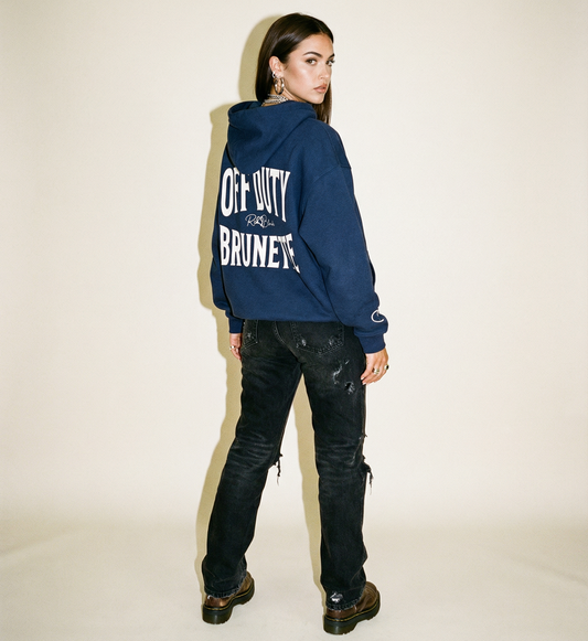 model wears Navy hoodie, back view, with large white ‘OFF DUTY BRUNETTE’ Brookfield text print and small RedBlonde  signature logo beneath.