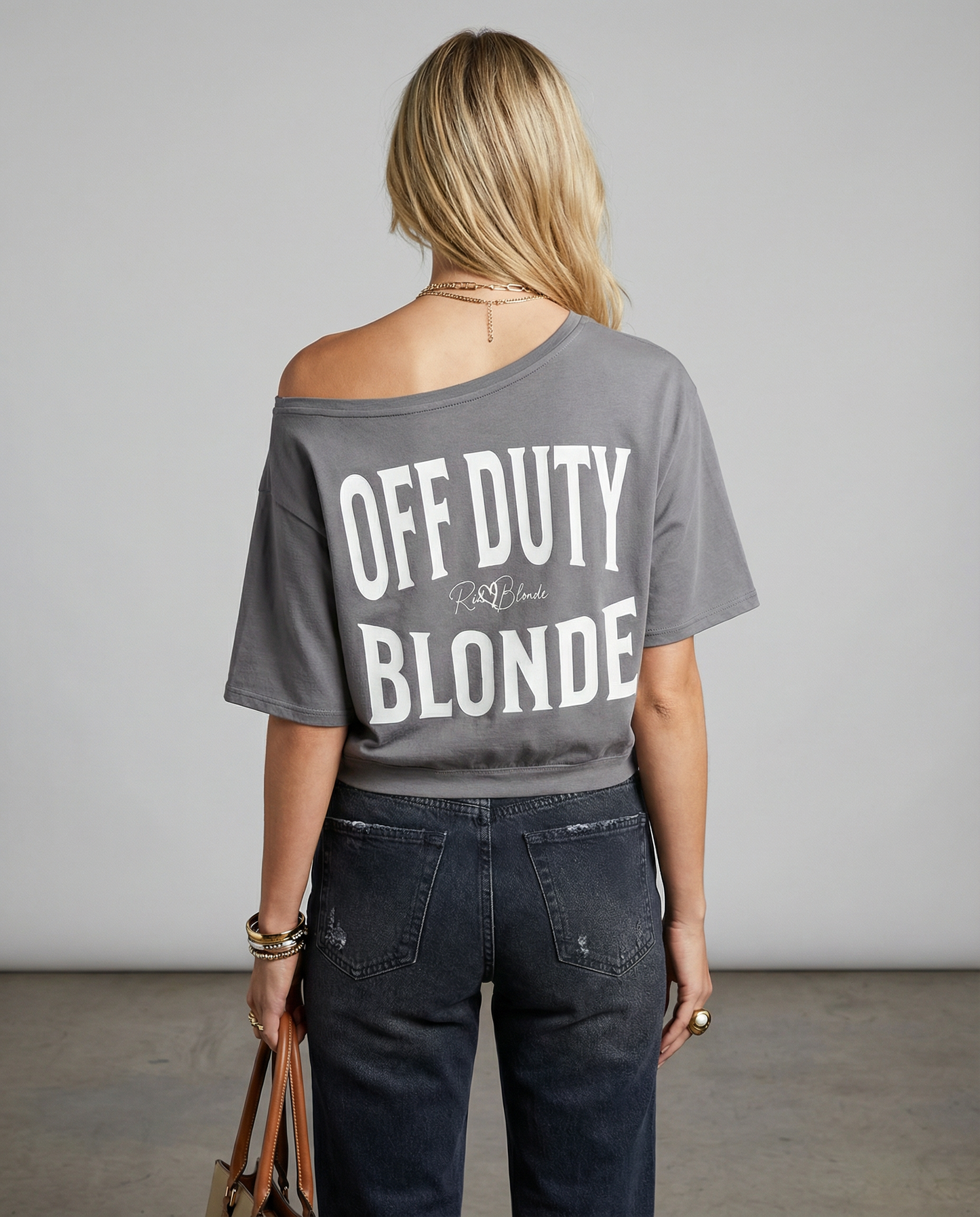 model wears a Grey asymmetrical boxy T-shirt with white ‘OFF DUTY BLONDE’  brookfield text back print and RedBlonde signature logo.”