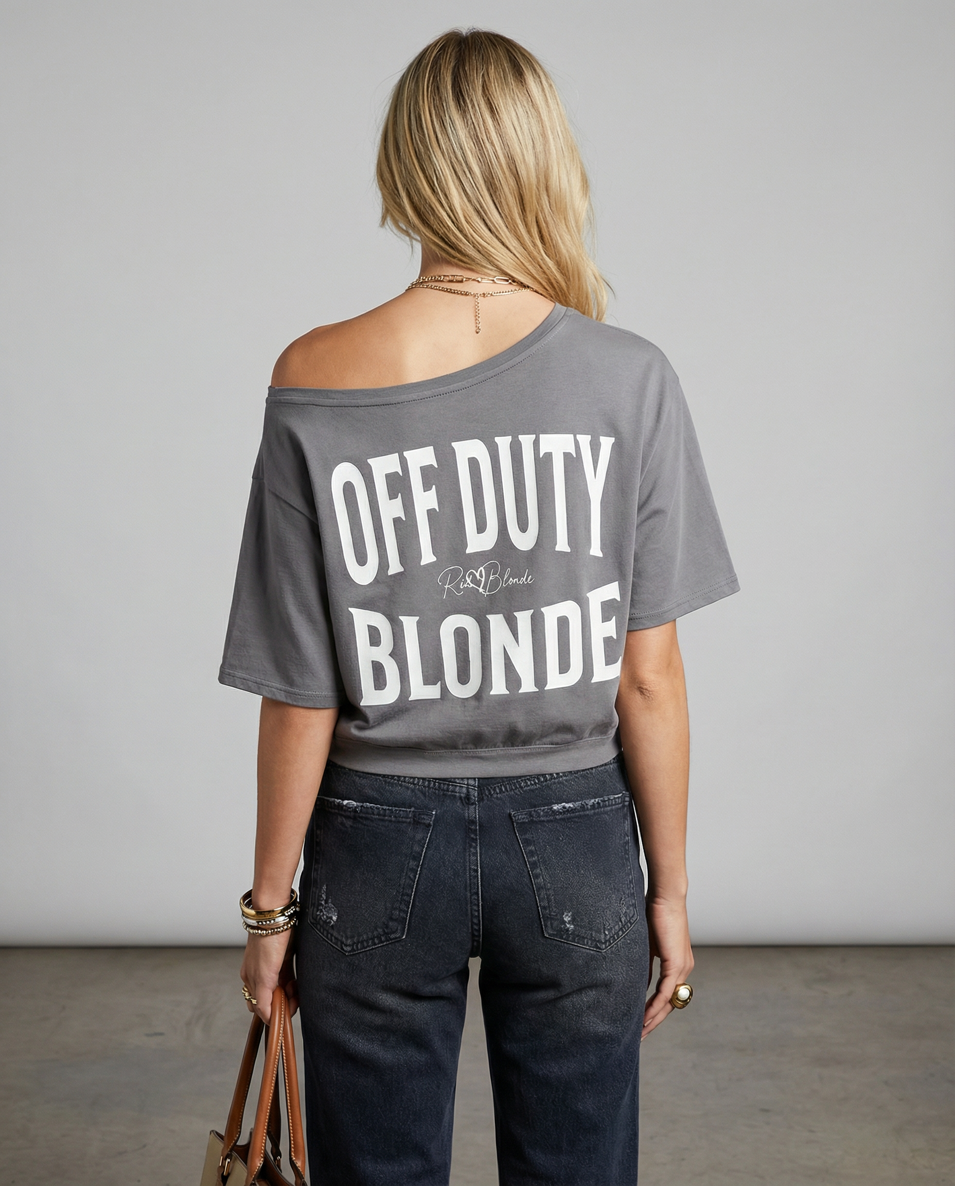 model wears a Grey asymmetrical boxy T-shirt with white ‘OFF DUTY BLONDE’  brookfield text back print and RedBlonde signature logo.”
