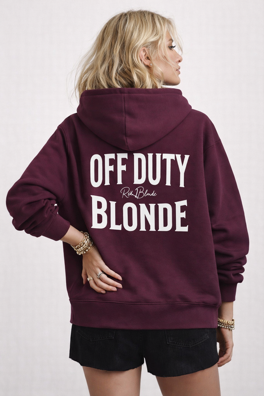 model wears a Plum oversized hoodie shown from the back featuring large white “OFF DUTY BLONDE” Brookfield text with a small RedBlonde script logo between the words.