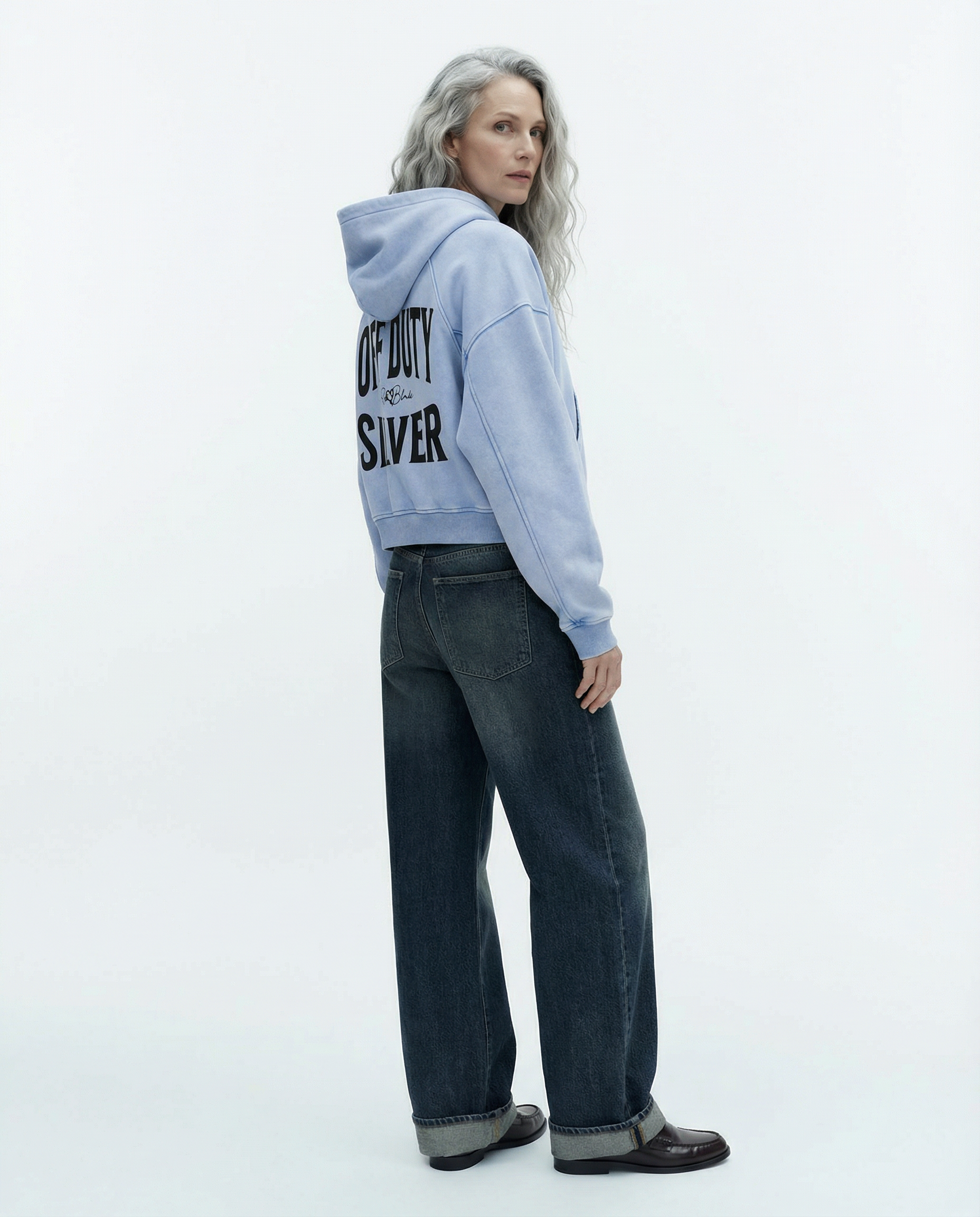 “Back view of model wearing a pale blue cropped hoodie with a hood and long sleeves, featuring large black ‘OFF DUTY SILVER' text and a small RedBlonde logo on the back.”