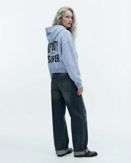 “Back view of model wearing a pale blue cropped hoodie with a hood and long sleeves, featuring large black ‘OFF DUTY SILVER' text and a small RedBlonde logo on the back.”