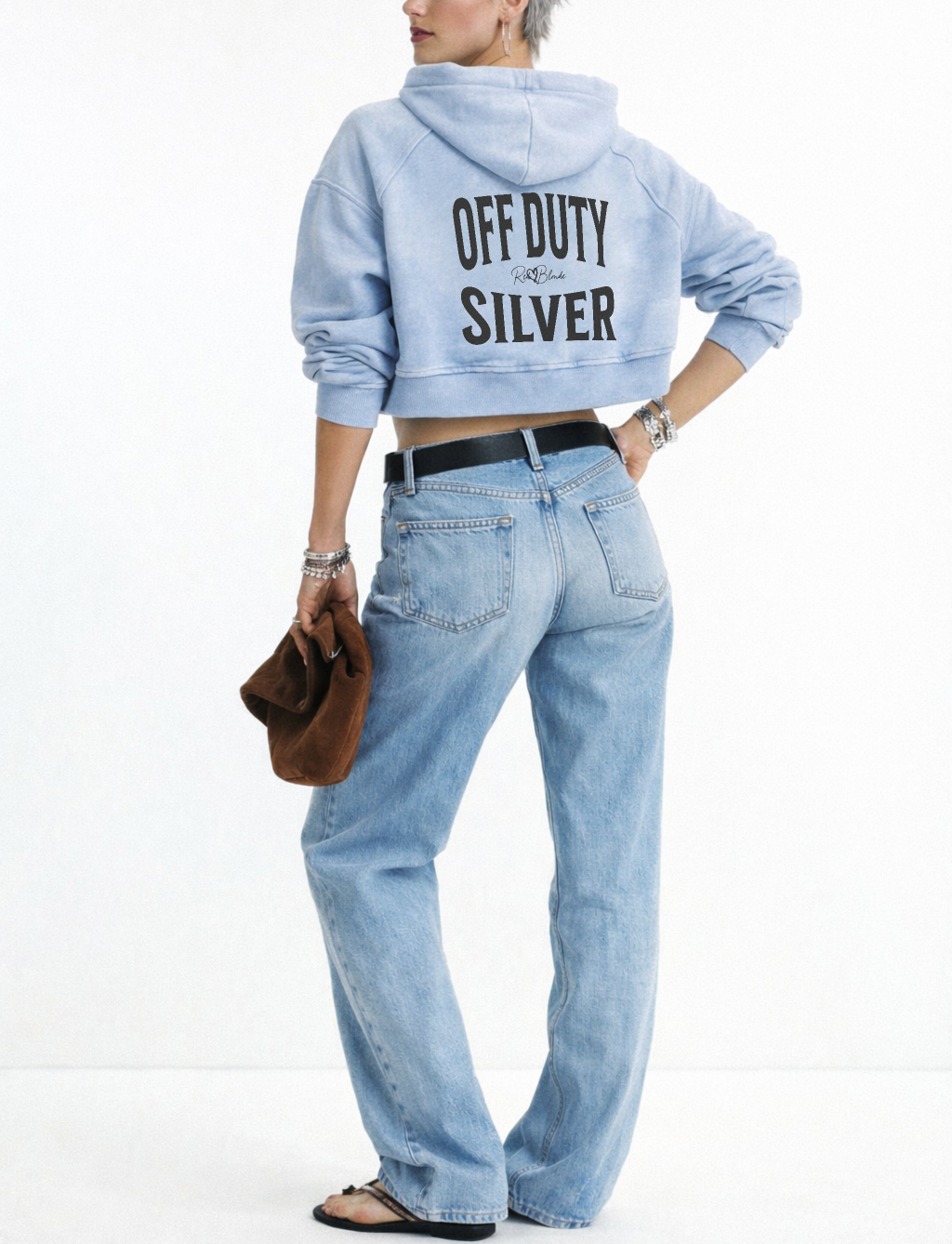 model wears a pale blue cropped hoodie with a hood and long sleeves, featuring large black ‘OFF DUTY SILVER' text and a small RedBlonde logo on the back.”