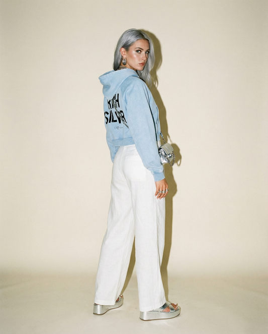 model wears a cropped snow-wash pale blue hoodie with bold black “RICH SILVER” Ed Gein font and the RedBlonde signature logo printed below.