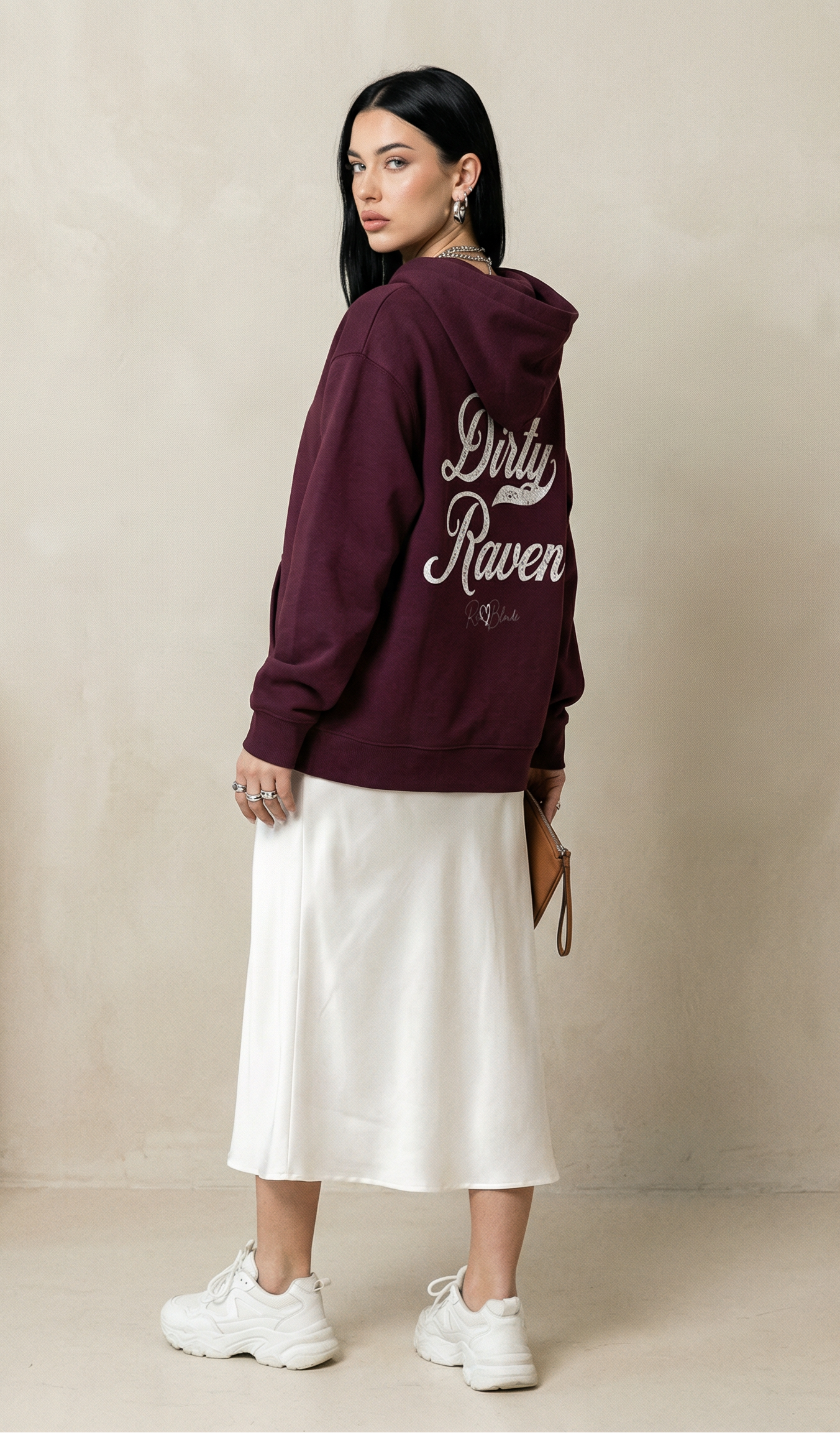 Raven haired Model wears a grey coloured hoodie with bold white Milkstore vintage-style script text “Dirty Raven” across the back and a subtle RedBlonde signature logo underneath.