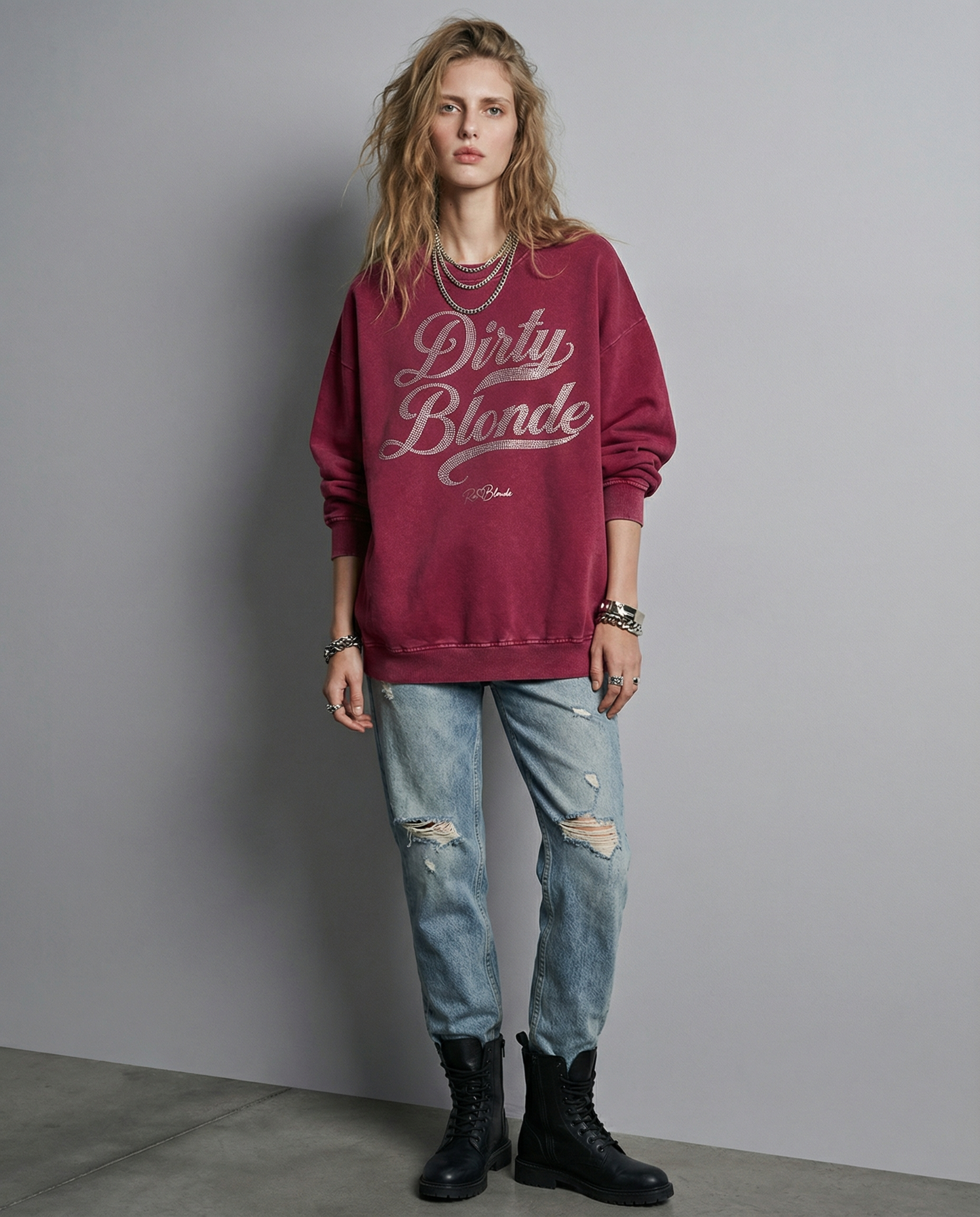Model wears Red snow-wash oversized sweatshirt with a drop-shoulder fit, featuring a rhinestone-style “Dirty Blonde” Milkstore script graphic across the front and a small RedBlonde logo near the hem.