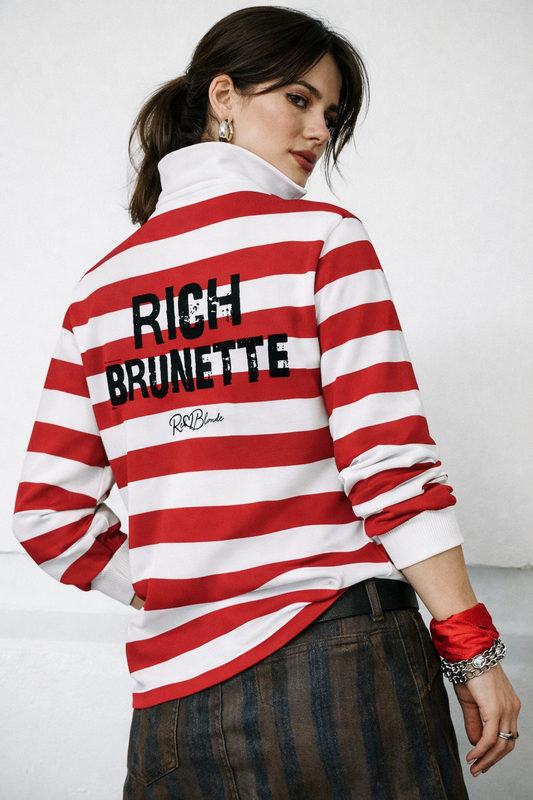 model wears a long-sleeved rugby polo shirt featuring a pattern of alternating horizontal red and white stripes. The center of the back displays the words "RICH BRUNETTE" in large, distressed Ed Gein black block lettering, with a smaller signature-style logo printed directly underneath. The shirt is finished with a solid white collar and matching white ribbed cuffs.