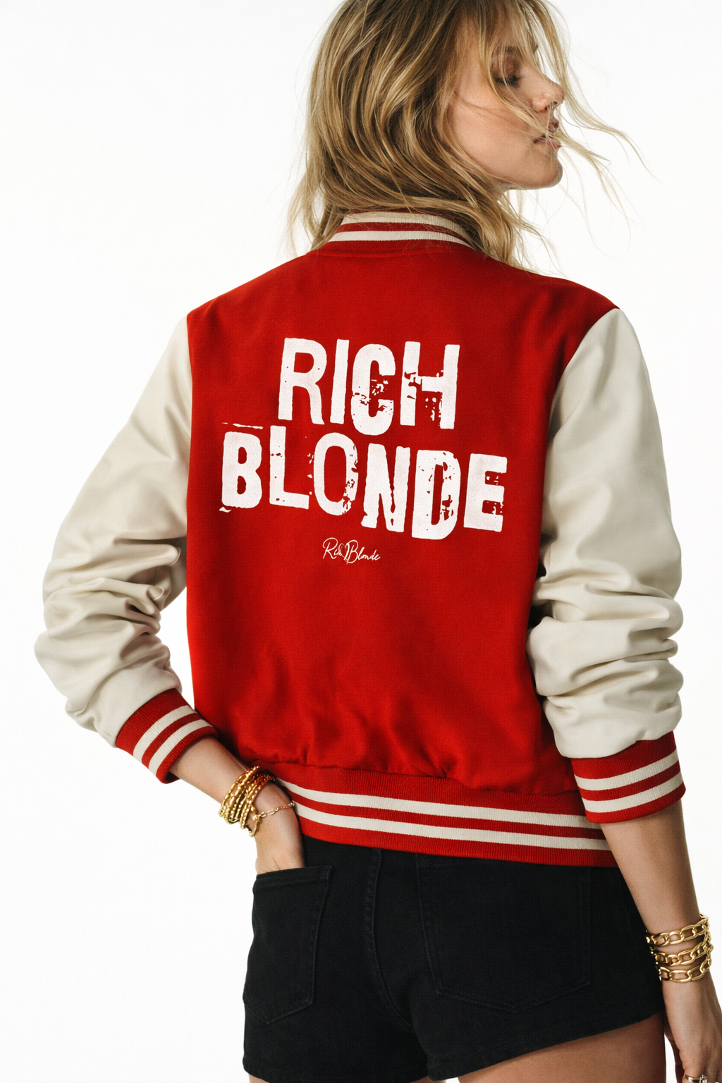 model wears a Red & white varsity-style jacket with cream sleeves and striped ribbed trims. The back features large white text reading “RICH BLONDE” in Ed Gein font with a small RedBlonde signature logo in the centre between the words
