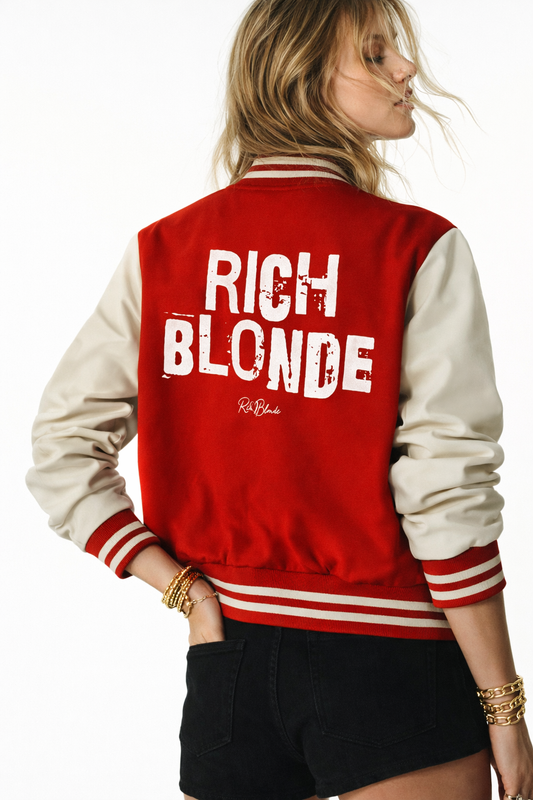 model wears a Red & white varsity-style jacket with cream sleeves and striped ribbed trims. The back features large white text reading “RICH BLONDE” in Ed Gein font with a small RedBlonde signature logo in the centre between the words