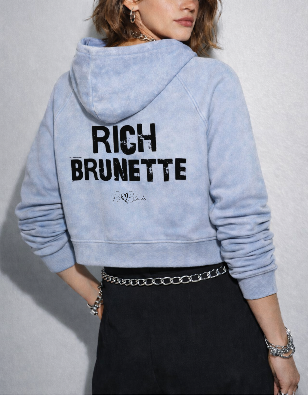 Back view of a cropped snow-wash pale blue hoodie with bold black “RICH BRUNETTE” Ed Gein font and the RedBlonde signature logo printed below.