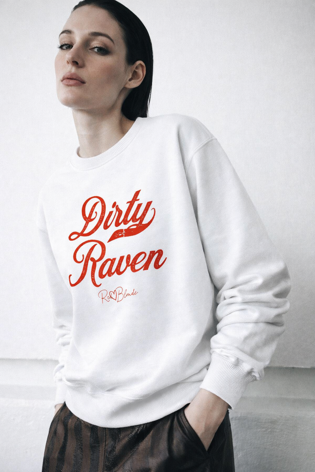 model wears white Classic relaxed fit premium unisex sweatshirt with the playful slogan ‘Dirty Raven’ in red milk-store font, signed off RedBlonde. 