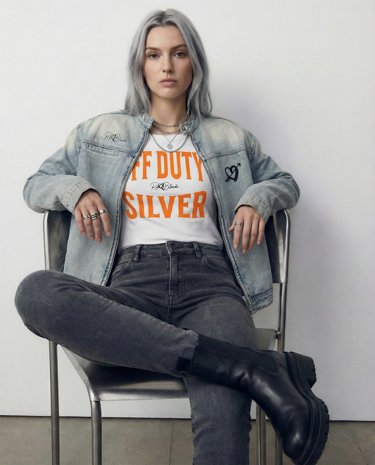 model wears a White raglan short-sleeve top with bold orange Brookfield lettering reading “OFF DUTY SILVER” with a small cursive RedBlonde logo between the words. and a denim RedBlonde jacket, she is sitting on a chair