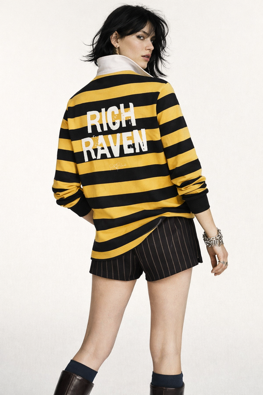 model wears a long-sleeved rugby polo shirt featuring a pattern of alternating horizontal yellow and navy stripes. The center of the back displays the words "RICH RAVEN" in large, distressed Ed Gein white block lettering, with a smaller signature-style logo printed directly underneath. The shirt is finished with a solid white collar and matching white ribbed cuffs.