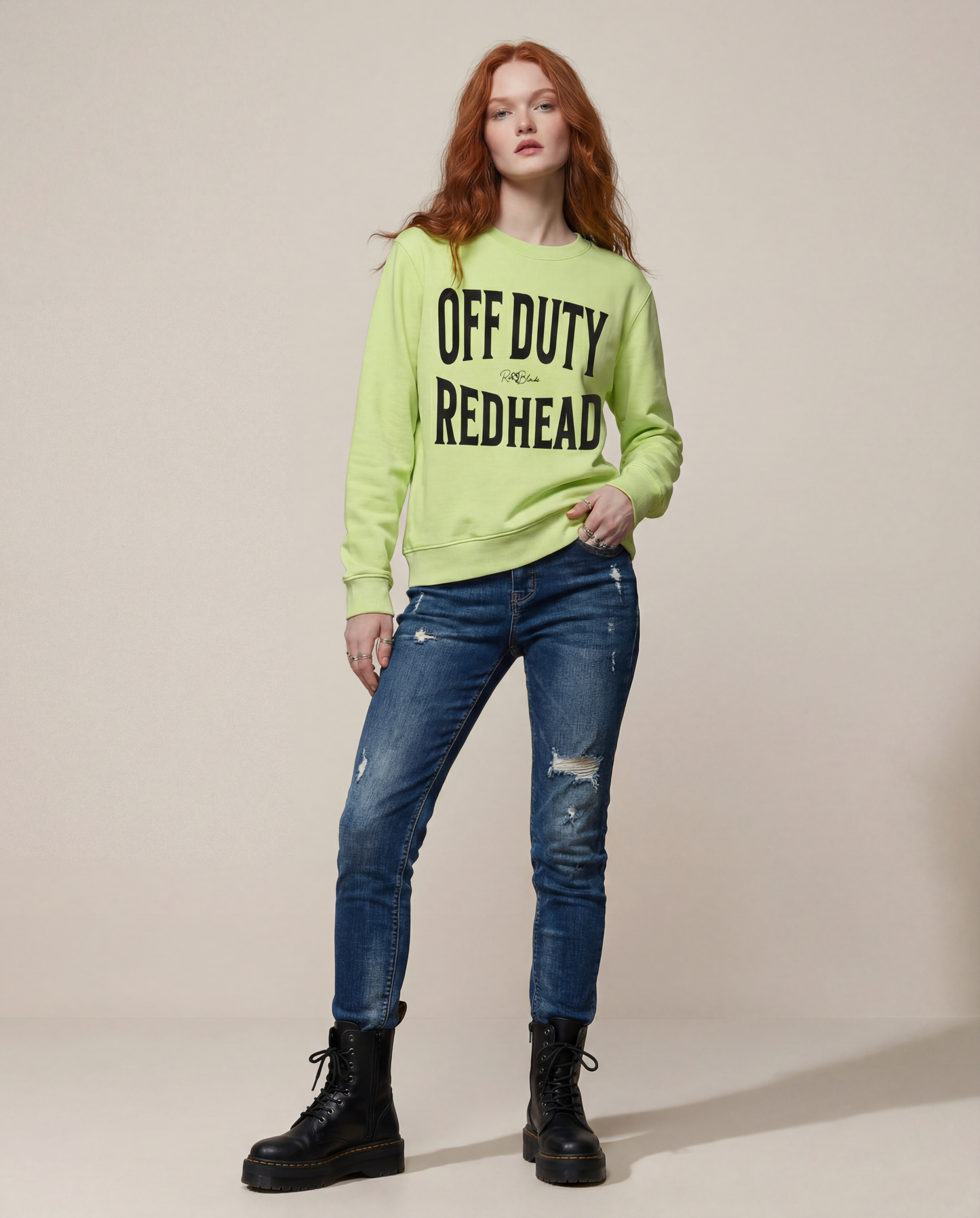 model wears neon yellow crewneck sweatshirt with a large black “OFF DUTY REDHEAD” graphic across the chest and a small RedBlonde script logo centered between the words.