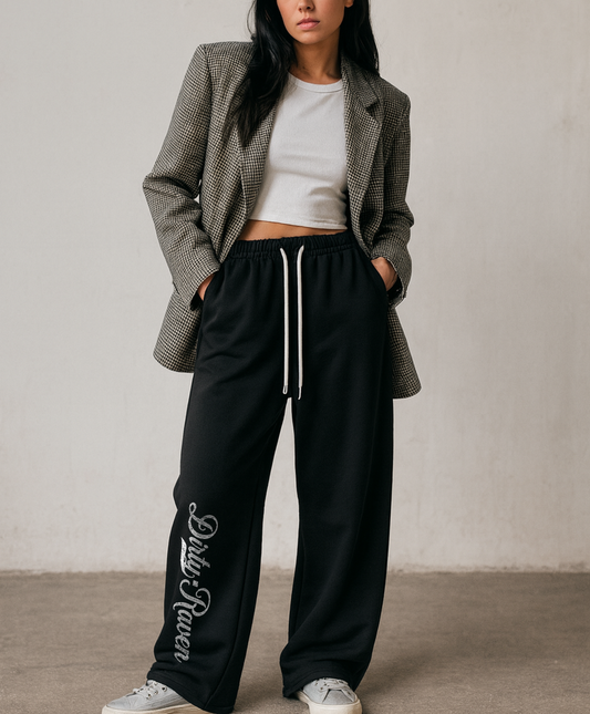 model wears a Black relaxed-fit straight joggers with white drawstrings and vintage-style “Dirty Raven” milkstore script printed vertically down the leg — bold, effortless and unmistakably RedBlonde.