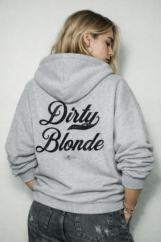 blonde model wearing  a grey hoodie with bold black Milkstore vintage-style script text “Dirty Blonde” across the back and a subtle RedBlonde signature logo underneath.