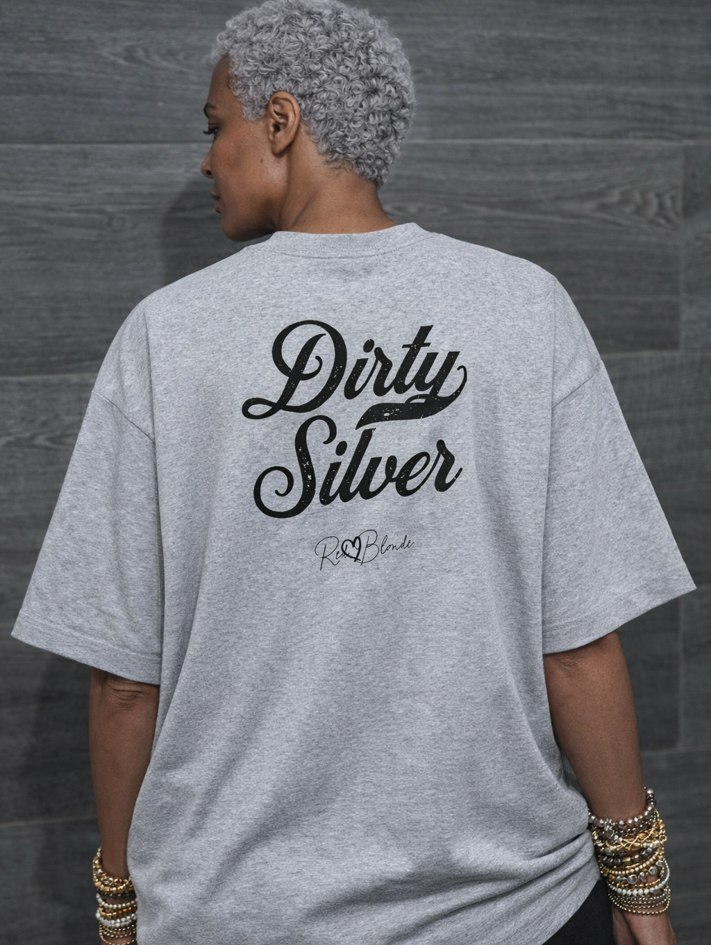 model wears a grey boxy oversized unisex T-shirt with bold black Milkstore 01 vintage-style script reading “Dirty Silver” and the RedBlonde signature logo beneath