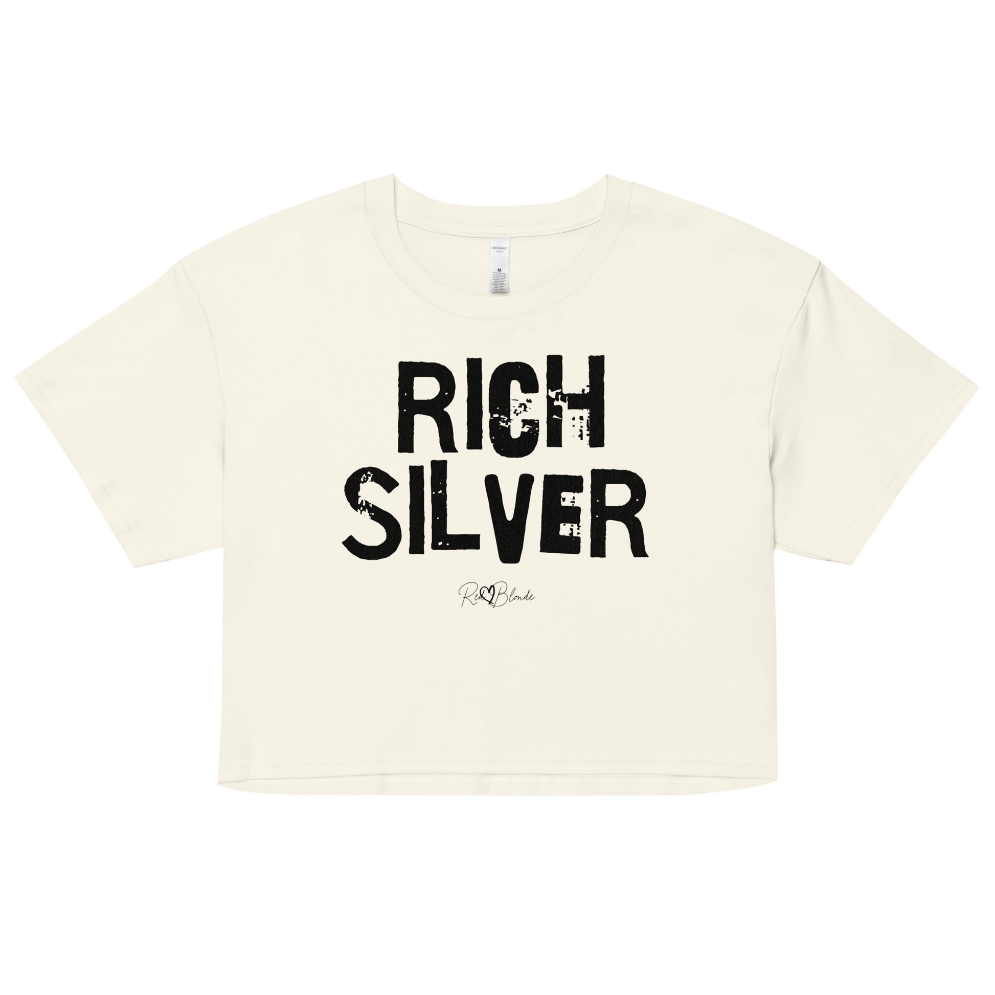 a natural coloured crop top with a relaxed fit, short sleeves, and a wide crew neckline. The front features bold black distressed lettering reading “RICH SILVER” with the RedBlonde signature logo underneath in black