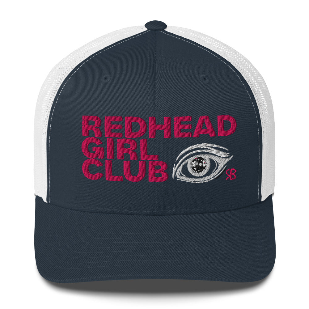 Navy/white mesh trucker hat featuring bold red embroidered text “Redhead Girl Club” alongside a detailed embroidered eye graphic and a small red RB logo.