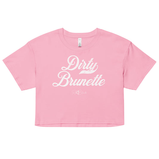 pink women’s crop top featuring the phrase “Dirty Brunette” in bold, white milkstore vintage-style script across the chest. Below the phrase, the brand name “RedBlonde” is printed in a smaller, elegant handwritten font.