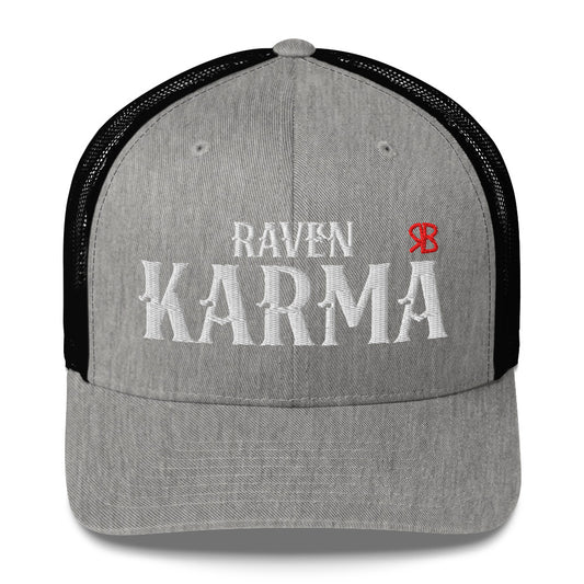 light grey / black retro trucker cap with mesh back. The front features bold white embroidered text reading "RAVEN KARMA" with a small red RB logo to the right.