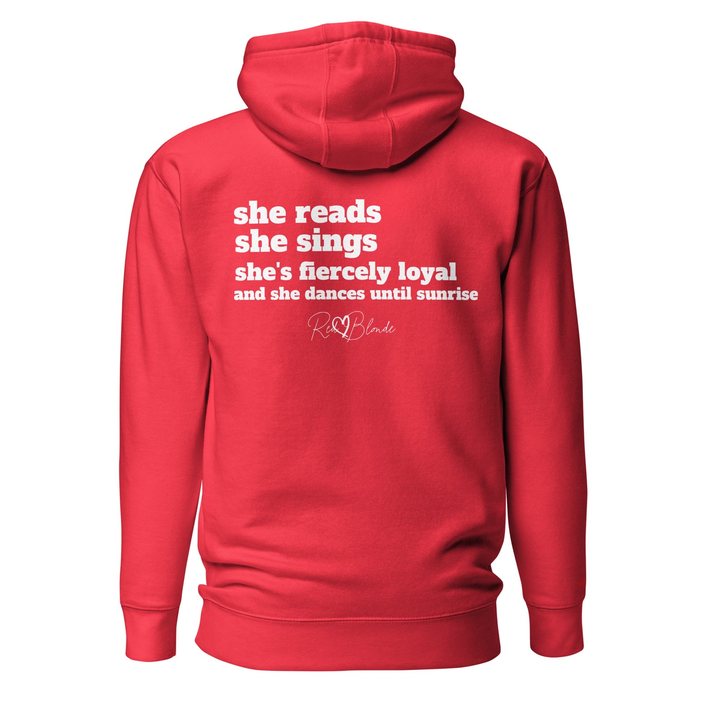 Back view of a red unisex hoodie featuring white text that reads, “she reads, she sings, she’s fiercely loyal, and she dances until sunrise,” with the RedBlonde logo printed underneath. The design conveys confidence and personality with a bold, uplifting message.