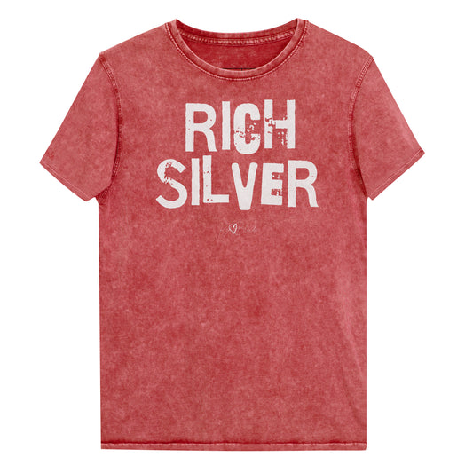 A garnet red acid-wash unisex denim T-shirt with a distressed vintage look. The shirt features the bold white text “RICH SILVER” in a weathered Ed Gein font, and features the RedBlonde signature logo. The shirt has short sleeves, a crew neckline, and visible seam detailing for a rugged, casual style. Branded Redblonde on inside neck and right sleeve