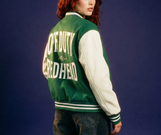 Redhead model wears Green varsity-style jacket with cream sleeves and striped ribbed trims. The back features large white text reading “OFF DUTY REDHEAD” in Brookfield font with a small RedBlonde signature logo in the centre between the words