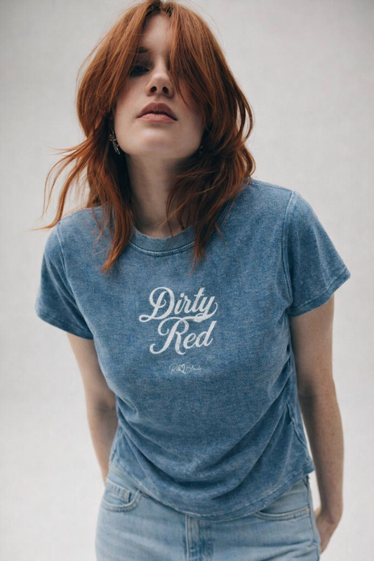Redhead models wears A fitted, short-sleeve blue crewneck T-shirt laid flat on a white background. It has subtle ruching/contouring at the sides and a slightly curved hem. White script text across the chest reads “Dirty Red,” in Milkstore 01 script with a small cursive “RedBlonde” logo beneath.
